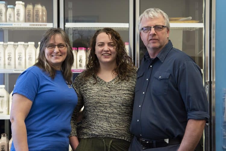 Wilma, Nicole, and Jim in front of milk display